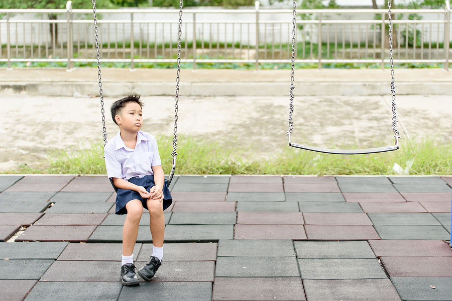 Young Thai student boy in school uniform sits and looks sad waiting for someone.